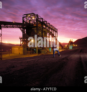 Nastro trasportatore che trasporta il minerale di rame nel frantumatore prima della lavorazione durante l'estrazione del rame al tramonto nel deserto di Atacama, Cile settentrionale Foto Stock