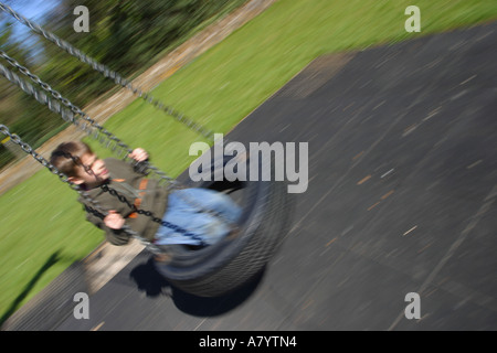 Ragazzo giocando sul parco giochi tire swing Foto Stock