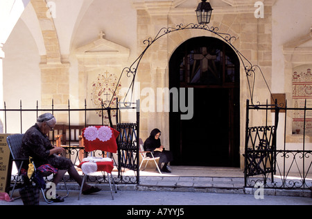 Cipro, regione centrale, Monti Troodos, Omodos viticoltura village, ricamatrice al frontdoor di Timios Stravos monastero Foto Stock