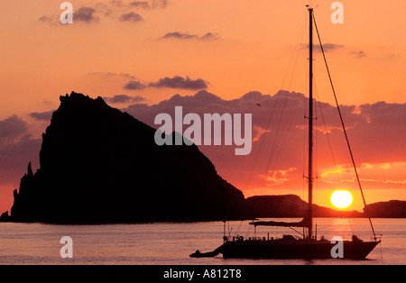 L'Italia, Sicilia e Isole Eolie, Ile de Panarea, barca a vela al tramonto la luce nella parte anteriore di un isolotto Foto Stock