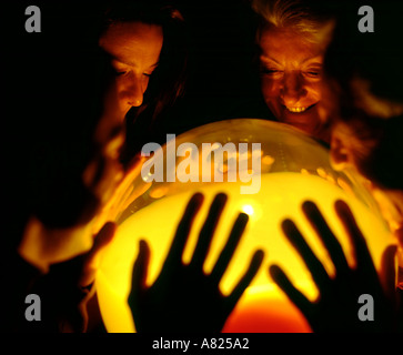 Famiglia guardando nella sfera di cristallo luce Foto Stock