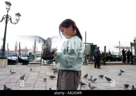 Una giovane ragazza alimenta i piccioni, Piazza San Marco, Venezia, Italia Foto Stock
