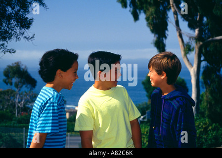 Giovane gente tre giovani ragazzi 11-13 anni vecchio appendere appendere fuori parco sulla collina che si affaccia sull'oceano di noi usa america myrleen pearson Foto Stock