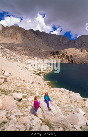 I bambini di età compresa tra 5 e 9 giocando su massi sopra il lago di pioppi neri americani John Muir Wilderness Sierra Nevada California Foto Stock