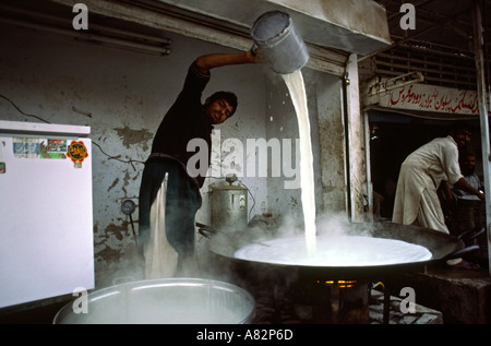 Il Pakistan a sud del Punjab uomo Bahawalpur versando il latte caldo in karahi Foto Stock