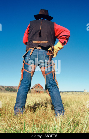 Un cowboy in piedi di fronte ad una cabina homestead pronto per disegnare un'arma da fuoco Foto Stock