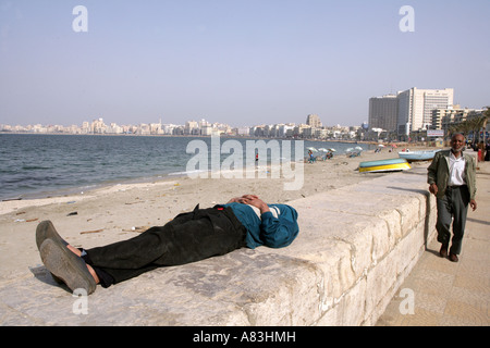 Uomo disteso sulla parete promenade, Corniche, Alessandria, Egitto, Medio Oriente Foto Stock