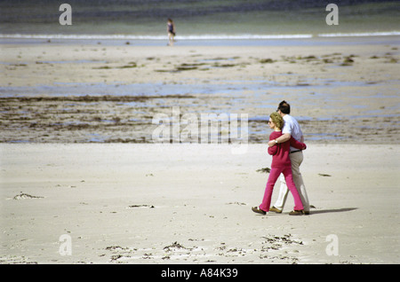 Coppia di mezza età passeggiare su una vasta spiaggia di sabbia Foto Stock