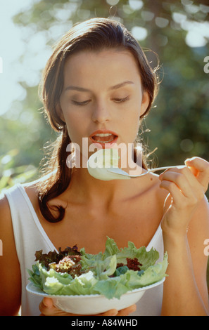 Outdoor closeup della giovane donna di mangiare una sana insalata verde. Foto Stock