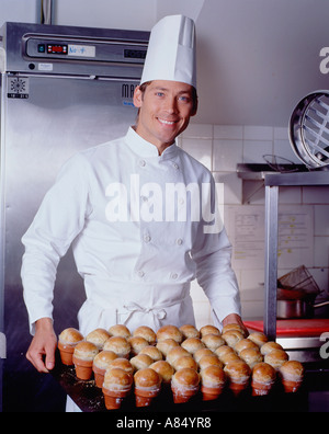 Chef nella cucina dell'hotel tenendo il vassoio di pane appena sfornato brioche panini. Foto Stock