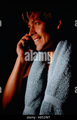 Piscina Ritratto di giovane con asciugamano attorno alle sue spalle utilizzando un telefono mobile. Foto Stock