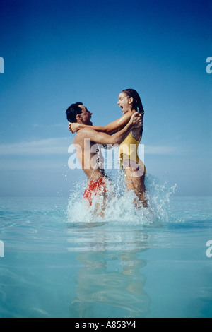 Maldive. Coppia giovane. Saltando in acqua al largo della spiaggia tropicale. Foto Stock