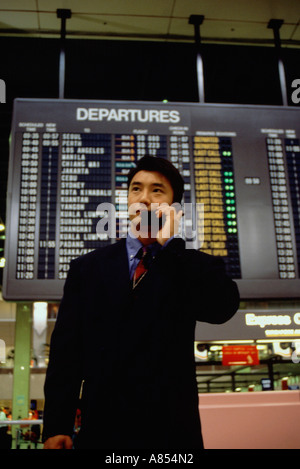 Giovane uomo che indossa una tuta di business, utilizzando un telefono mobile all'interno di terminal di un aeroporto. Foto Stock