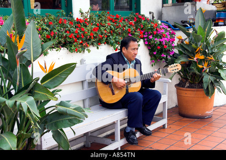 Un animatore di strada di suonare una chitarra circondato da fiori colorati nella storica Città Vecchia di San Diego California USA Foto Stock