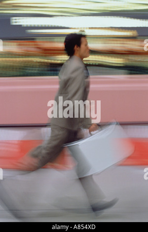 Giovane uomo in airport terminal correre per prendere il suo volo. Foto Stock