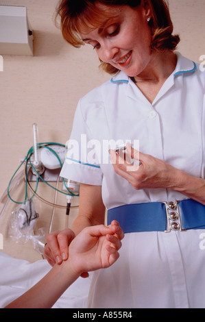 Ospedale pediatrico infermiere impulso prendendo la frequenza cardiaca della ragazza giovane bambino paziente. Il braccio di close-up. Foto Stock