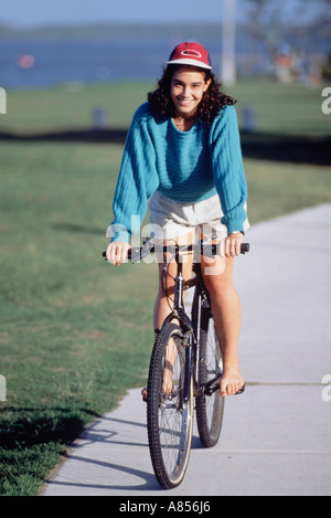 Giovane donna in bicicletta nel waterside park. Foto Stock