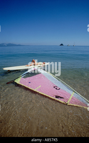 Australia. Queensland. Dunk Island. Giovane donna sdraiata su una tavola a vela. Foto Stock