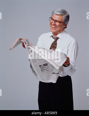 Uomo di mezza età leggendo il giornale in studio. Foto Stock