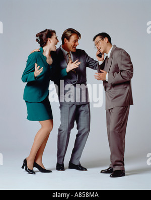 Studio Immagine di un gruppo di tre colleghi di lavoro a congratularci gli uni con gli altri mentre l'udito la Buona Novella dal telefono mobile. Foto Stock