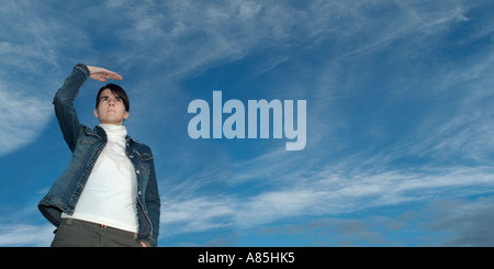 Coppia brunette donna che guarda fuori attraverso il cielo blu con la sua mano schermare gli occhi dal sole Foto Stock