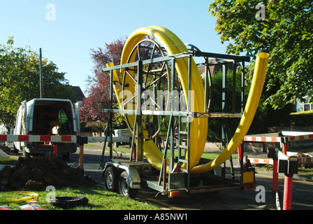 Gas principale posa di tubi lavori stradali in corso con grande bobina di tubo di plastica flessibile giallo sul rimorchio Essex Inghilterra UK con spazio di copia Foto Stock