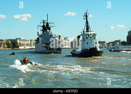 L'alta marea del Tamigi frega F99 Cornovaglia assistita da rimorchiatori durante le manovre di svolta dopo la partenza in giornata dal Pool of London Inghilterra Regno Unito Foto Stock