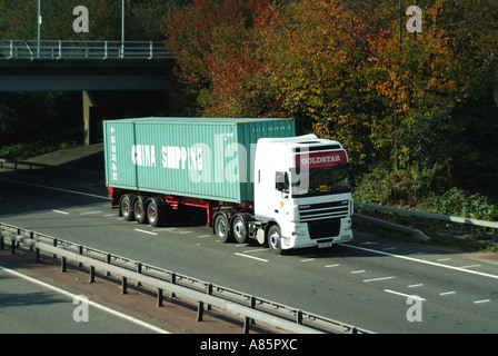 Cina contenitore di spedizione su rimorchio di autocarro articolato hgv su strada a due carreggiate che passa sotto il ponte nel taglio A12 Essex Inghilterra UK Foto Stock