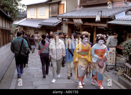 Due maiko o geisha in formazione, camminando lungo una stretta stradina acciottolata in Kyoto Higashiyama district. Foto Stock