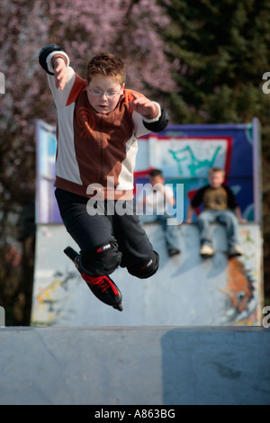 Un giovane skater è la pratica di salto con i suoi pattini Foto Stock