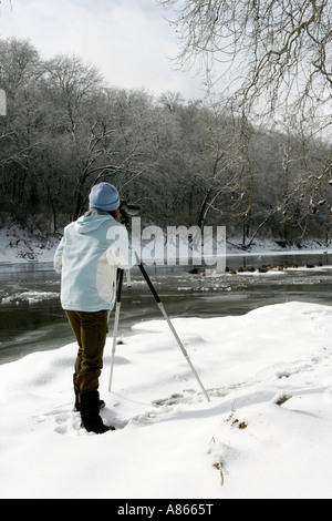 Inverno di osservazione degli uccelli con cannocchiale lungo il fiume nevoso Bank - Verticale Foto Stock