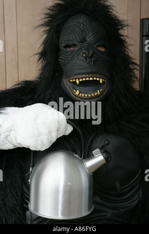 Vista della persona in costume gorilla tenendo un bollitore. Foto Stock