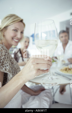 Le donne tenendo in mano un bicchiere di vino tra un gruppo Foto Stock