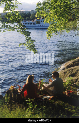 Giovane avente picnic al tramonto lungo la via navigabile di Stoccolma Foto Stock