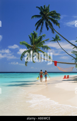 Giovane camminando mano nella mano sulla riva sabbiosa sull isola di Fihalhohi delle Maldive Foto Stock