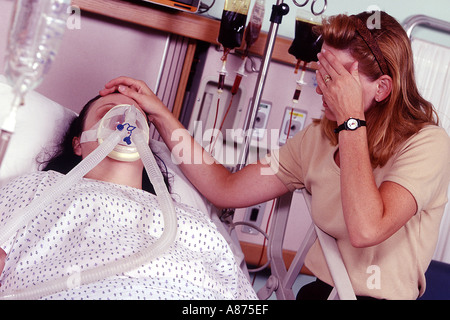 Sconvolta donna seduta accanto al paziente di sesso femminile di indossare le maschere di ossigeno Foto Stock