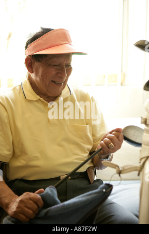 Senior pulizia uomo golf club, sorridente Foto Stock