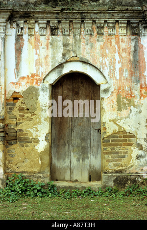 Vecchio arcuata di porta di legno nella frantumazione parete spiovente di un abbandonato stile coloniale Francese villa, Bac Ha, NW Viet Nam Foto Stock