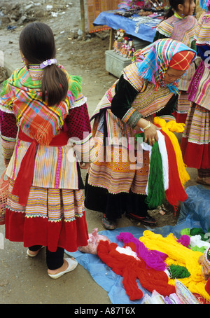 Tradizionalmente condita fiore donna Hmong e ragazza a una pressione di stallo di lana, mercato di domenica, Bac Ha, NW Viet Nam Foto Stock