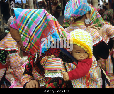 Tradizionalmente condita Flower Hmong Donna con bambino in un supporto posteriore, al mercato del sabato, può cau, NW Viet Nam Foto Stock