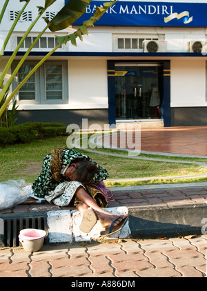 Anziana donna locale di accattonaggio in strada vicino a una banca di yogyakarta indonesia java Foto Stock