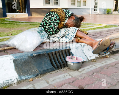 Anziana donna locale di accattonaggio in strada vicino a una banca di yogyakarta indonesia java Foto Stock