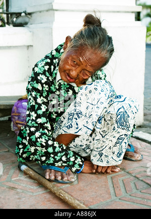 Anziana donna locale di accattonaggio in strada vicino a una banca di yogyakarta indonesia java Foto Stock