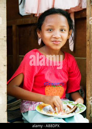 Ragazza giovane mangiare pasti in delle baraccopoli di Surabaya, Java,Indonesia Foto Stock