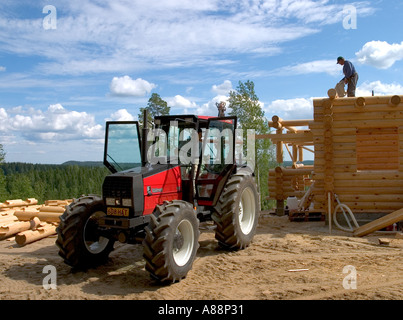 Valmet trattore e un uomo anziano sul tetto e installare nuove esitano di fronte al log cabin parete , Finlandia Foto Stock