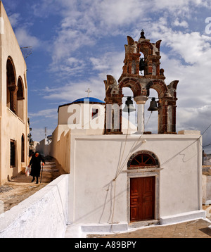 Una vecchia donna vestita di nero chiesa con campanile a torre, Pyrgos, Santorini, Grecia Foto Stock