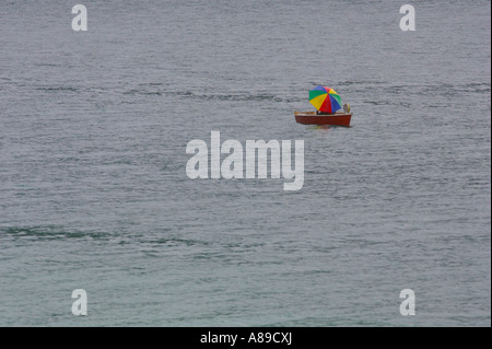 Il pescatore con ombrellone in rosso barca a remi sul lago di Walchen, Alta Baviera, Baviera, Germania Foto Stock