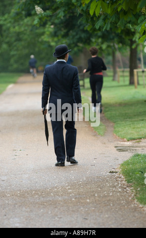 Uomo in smart city tuta e cappello bowler passeggiando in Hyde Park Londra Foto Stock