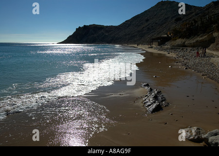 Spiaggia di sabbia scena ben retroilluminata con buone onde e cielo blu a Burgau Algarve Portogallo Foto Stock