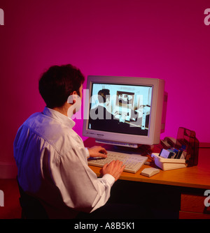 Uomo al computer che guarda nel passato sul suo PC desktop nel 1990s Foto Stock